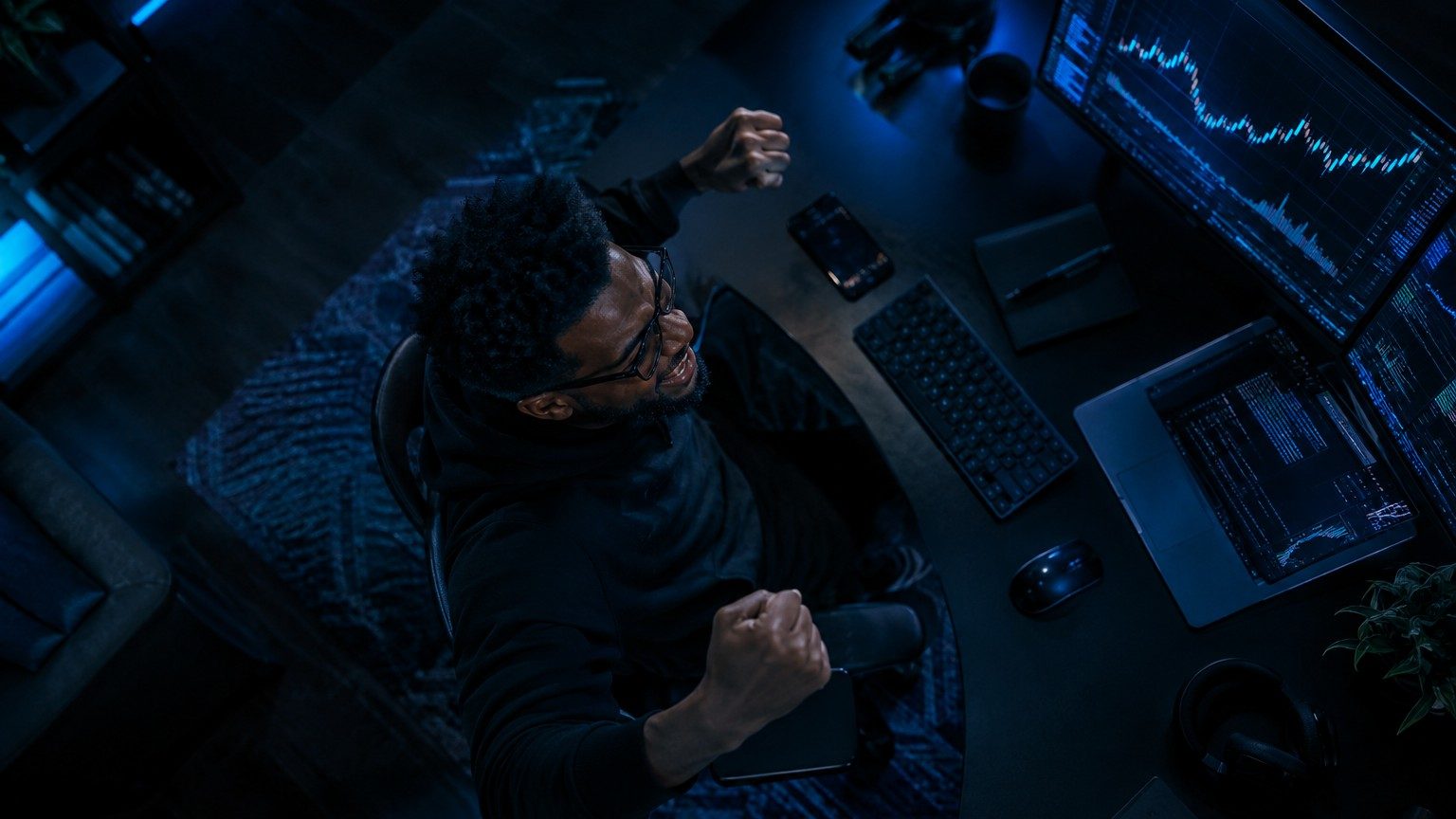 Fintech engineer celebrating a successful trade at his desk, cinematic still