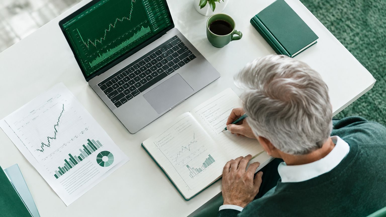 Senior investor with gray hair taking notes during a market analysis session